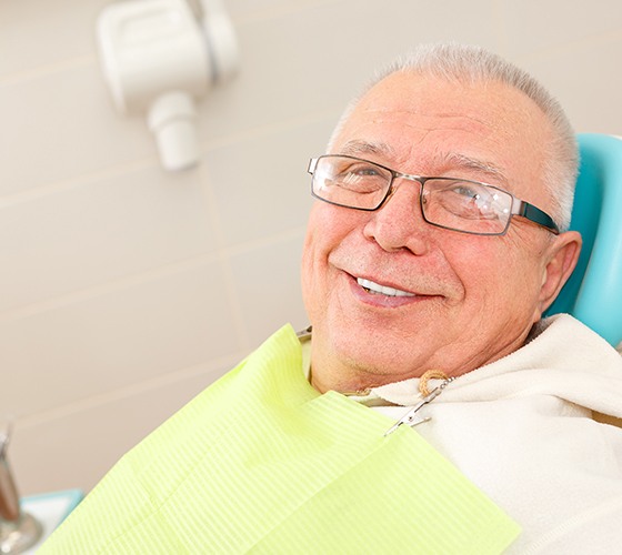 Man in dental chair for emergency dentistry smiling