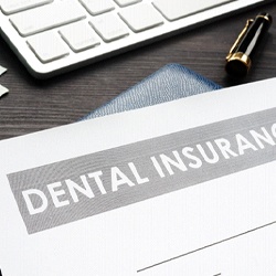 Dental insurance form on a desk with keyboard and money