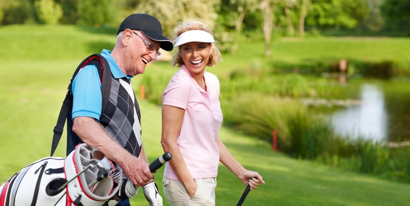 Older man and woman smiling together on the golf course