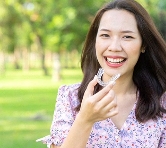 A patient holding her Invisalign aligner in Lady Lake, FL
